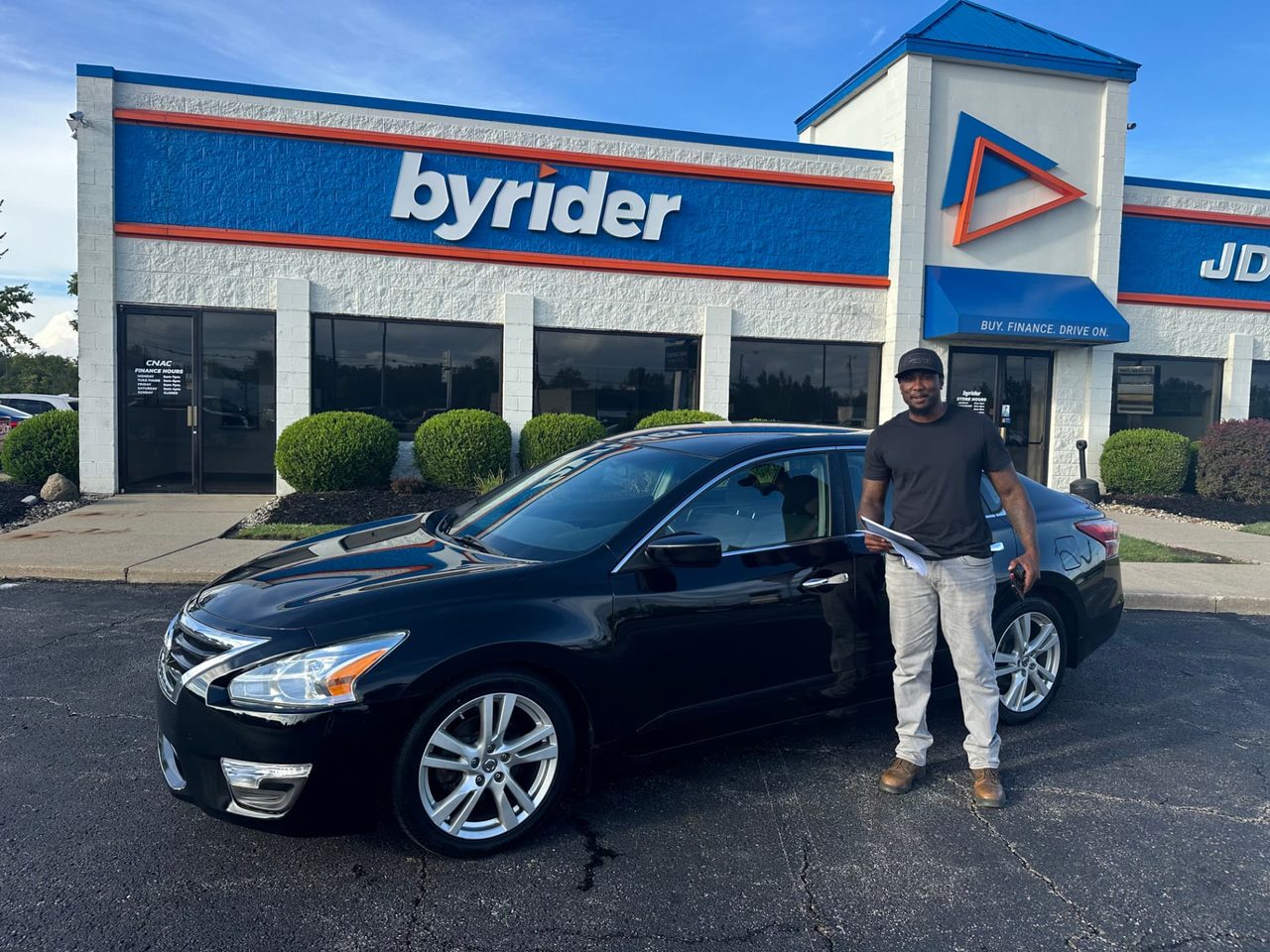 Byrider Mansfield customer and salesperson beside their used Nissan Altima at the Mansfield, Ohio dealership