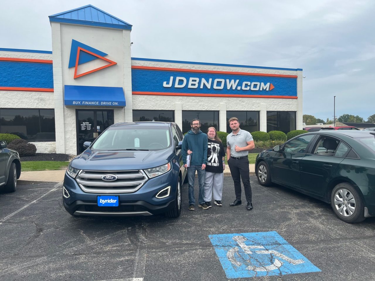 Byrider Mansfield customers and salesperson beside their used Ford Edge at the Mansfield, Ohio dealership