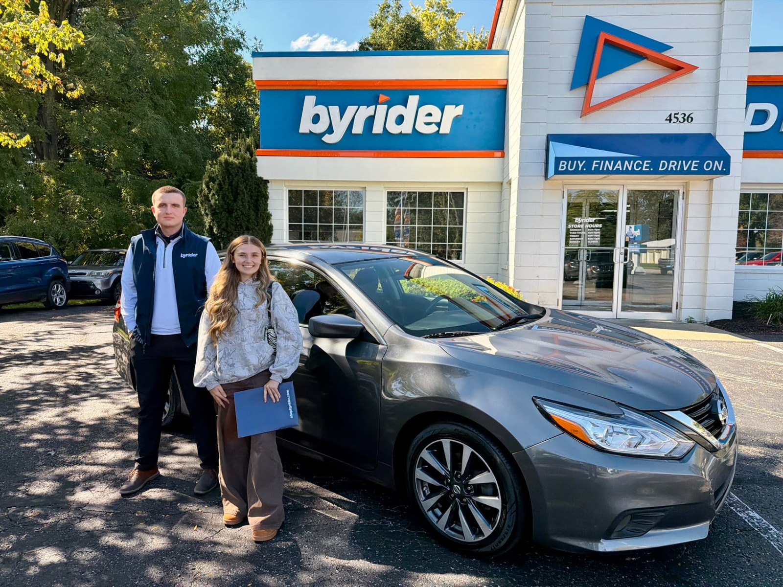 Byrider Wooster customer and salesperson beside their used Nissan Altima at the Wooster, Ohio dealership