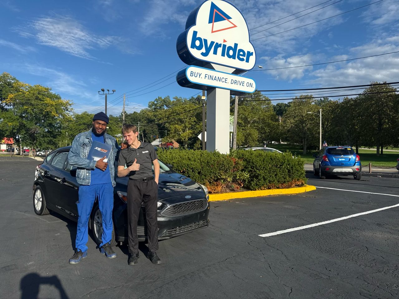 Byrider Euclid customer and salesperson beside their used Ford Focus at the Euclid, Ohio dealership
