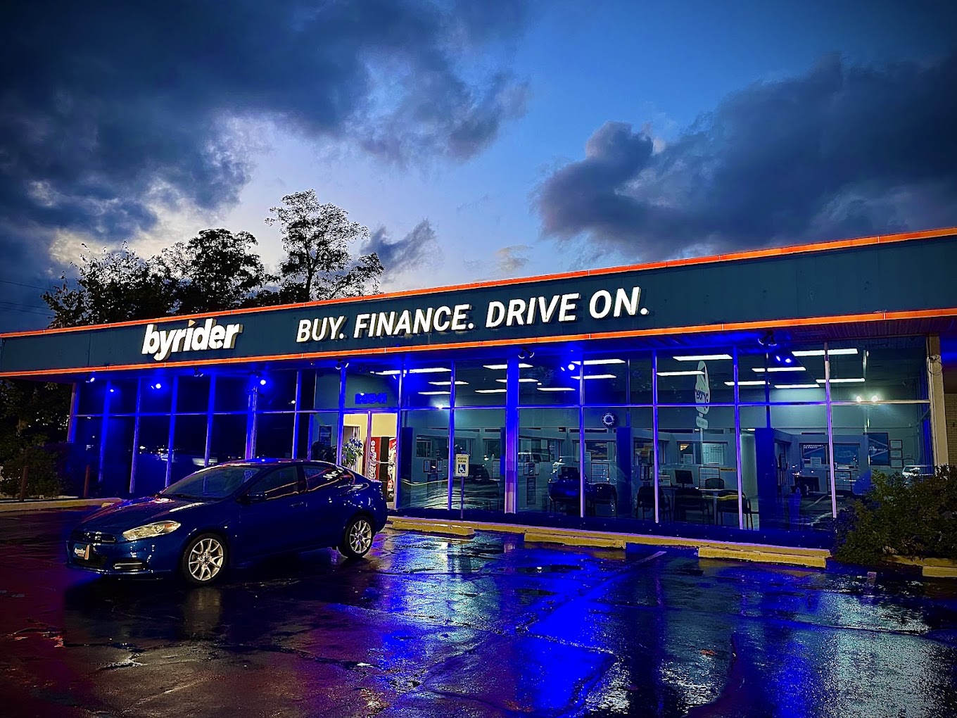Byrider Euclid used car dealership storefront at 20941 Euclid Ave, Euclid, Ohio, lit up in blue at dusk