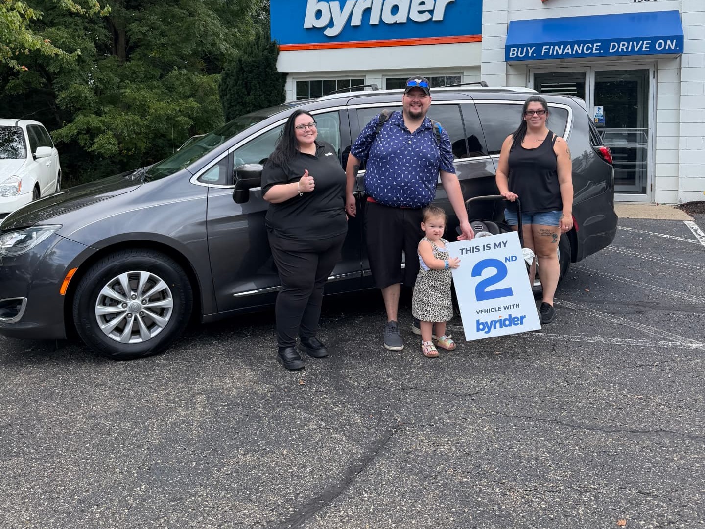 Byrider Wooster customers and salesperson beside their used Chrysler Pacifica at the Wooster, Ohio dealership