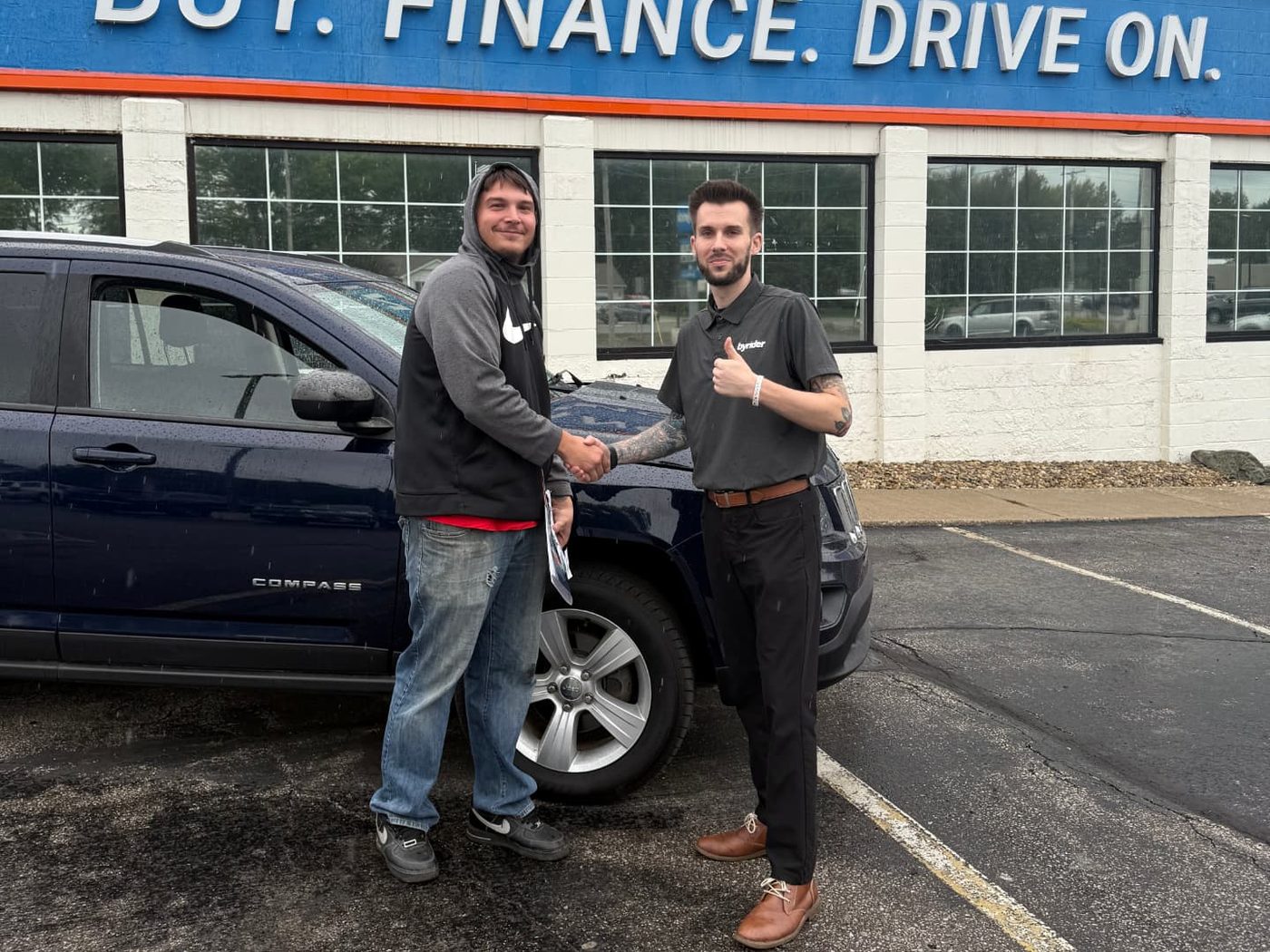 Byrider Amherst customer and salesperson beside their used Jeep Compass at the Amherst, Ohio dealership