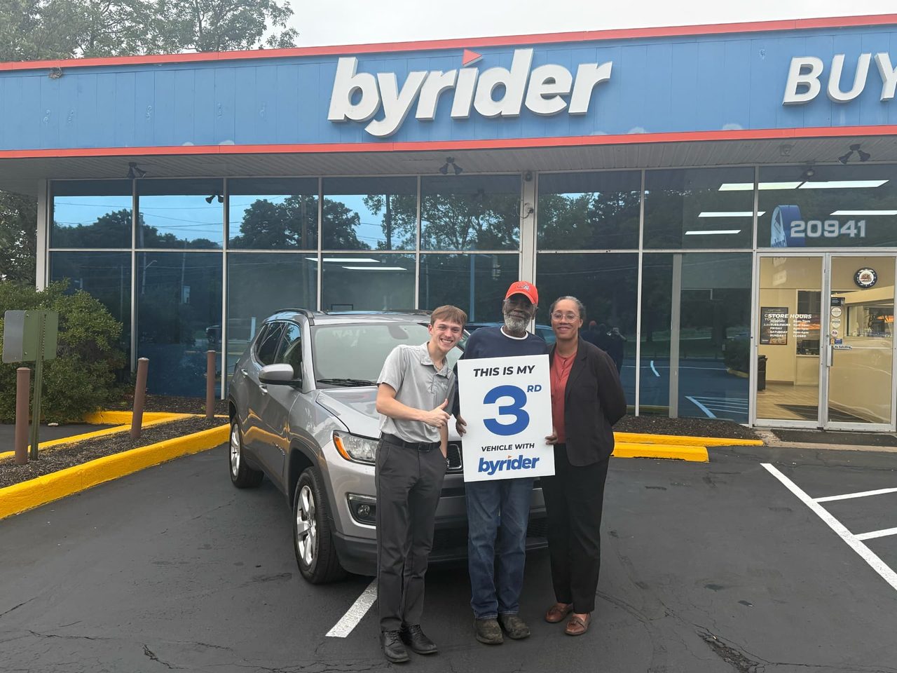 Byrider Euclid customers and salesperson beside their used Jeep Compass at the Euclid, Ohio dealership