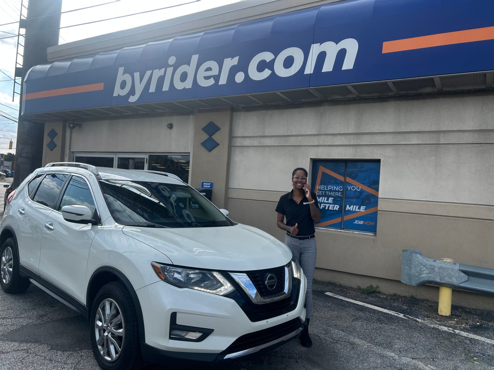 Byrider Cleveland customer and salesperson beside their used Nissan Rogue at the Cleveland, Ohio dealership