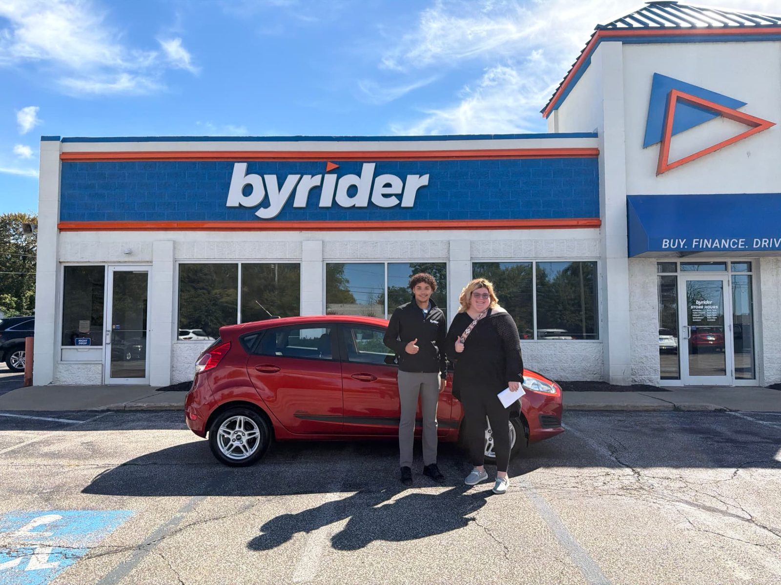 Byrider Ashtabula customer and salesperson beside their used Ford Fiesta at the Ashtabula, Ohio dealership