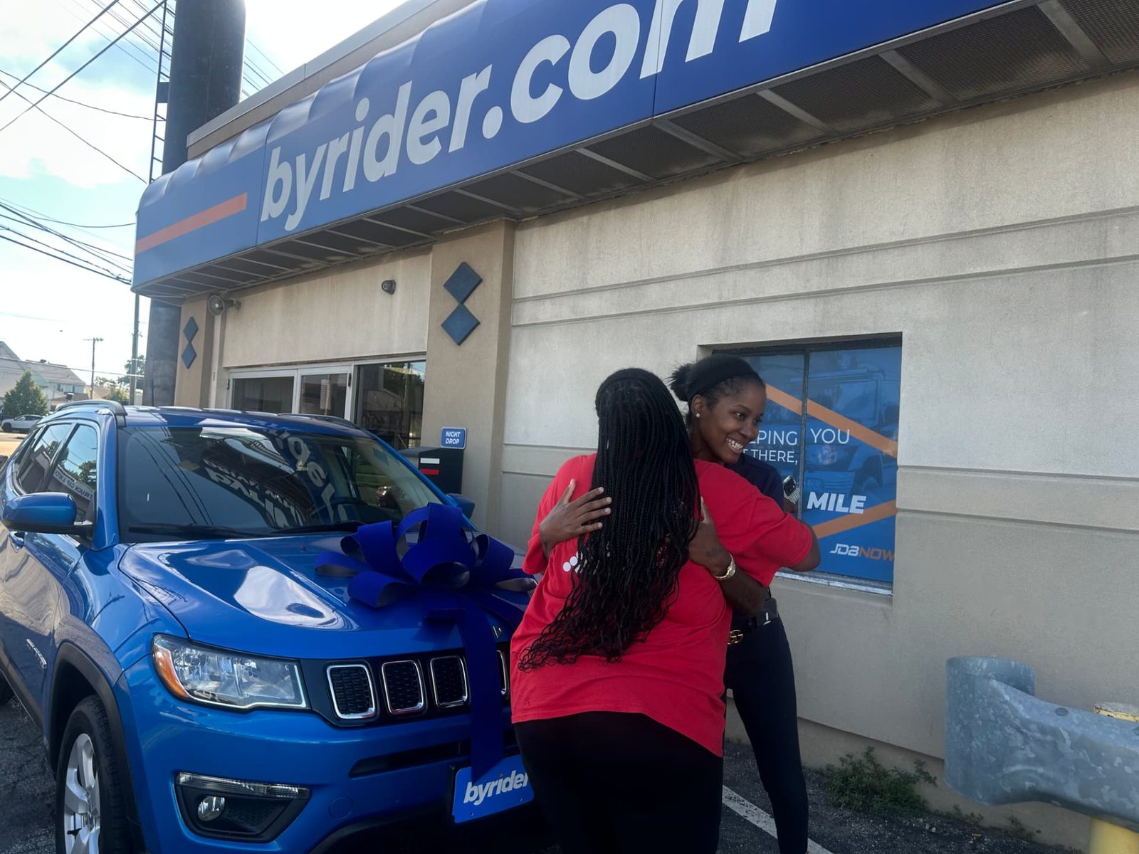 Byrider Cleveland customer and salesperson beside their used Jeep Compass at the Cleveland, Ohio dealership