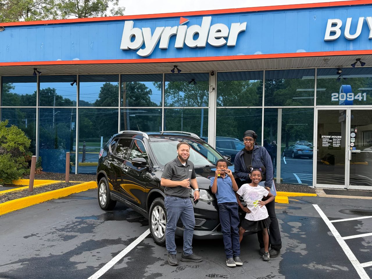 Byrider Euclid customers and salesperson beside their used Nissan Rogue at the Euclid, Ohio dealership