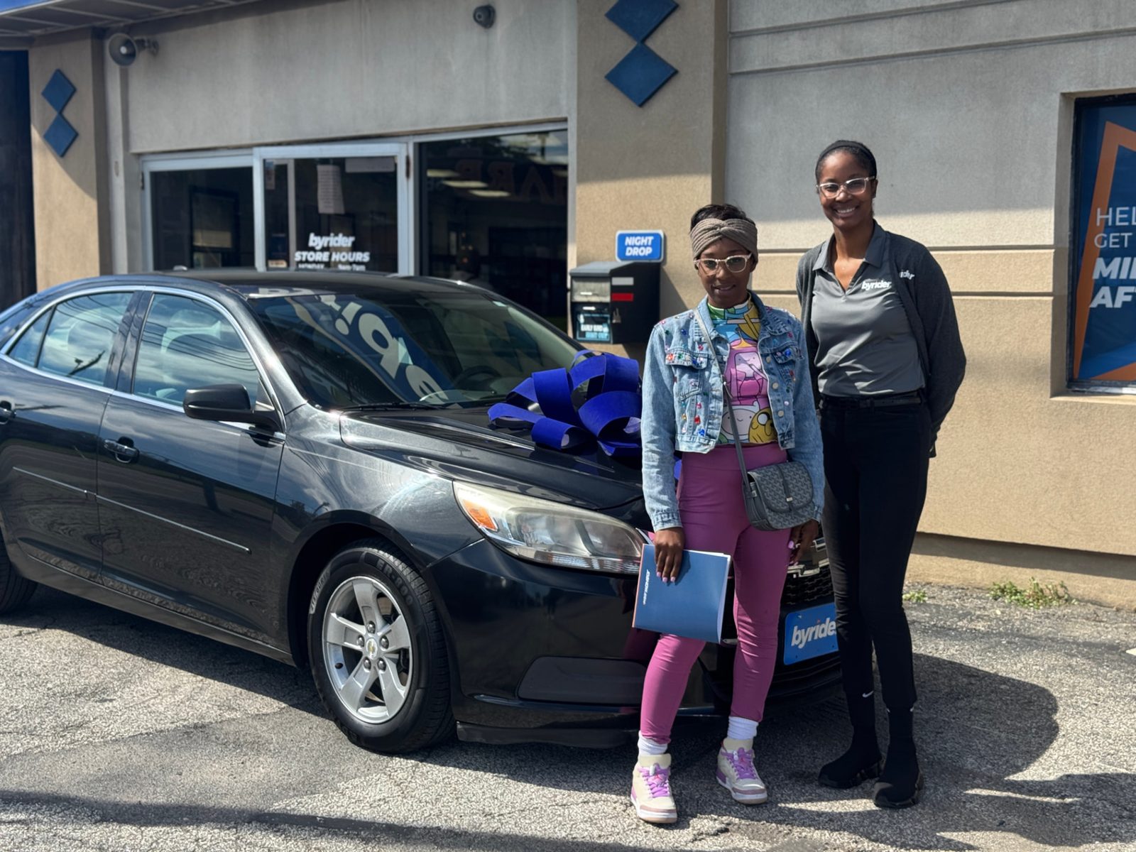 Byrider Cleveland customer and salesperson beside their used Chevrolet Malibu at the Cleveland, Ohio dealership