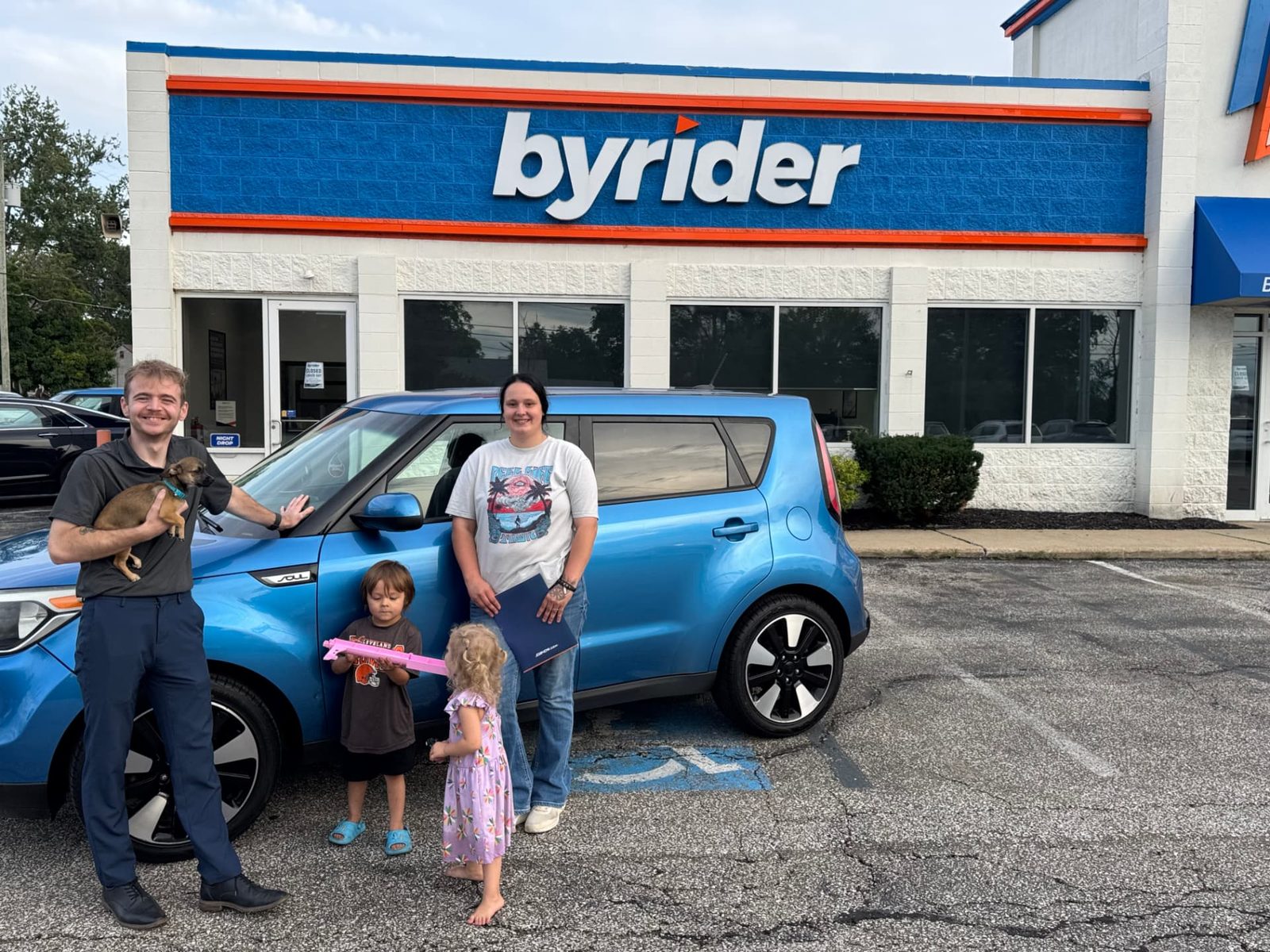 Byrider Ashtabula customers and salesperson beside their used Kia Soul at the Ashtabula, Ohio dealership