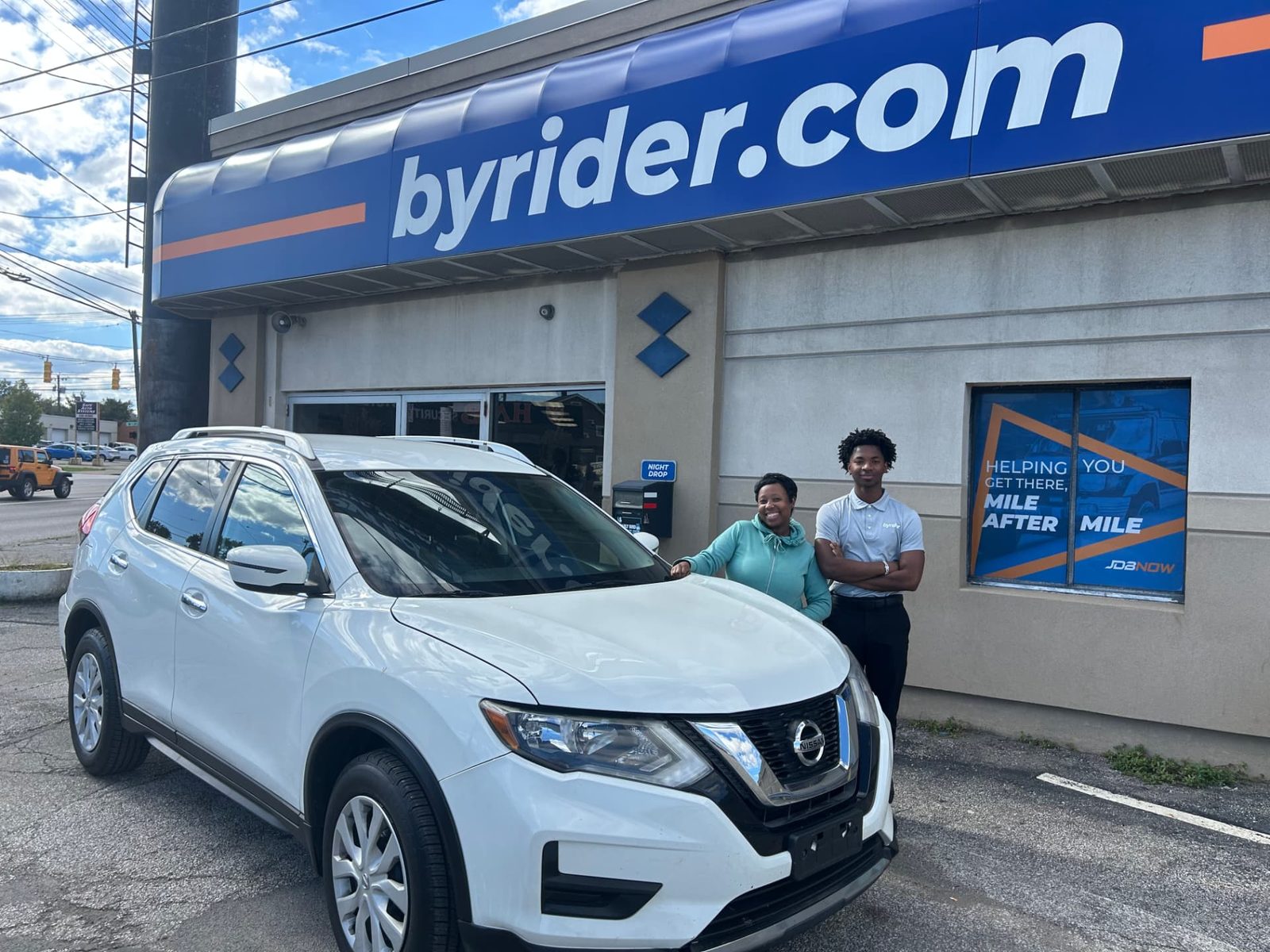 Byrider Cleveland customer and salesperson beside their used Nissan Rogue at the Cleveland, Ohio dealership
