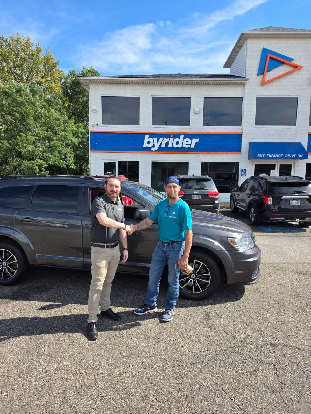 Happy Byrider Akron customer shaking hands after buying a used Dodge Journey in Akron, Ohio