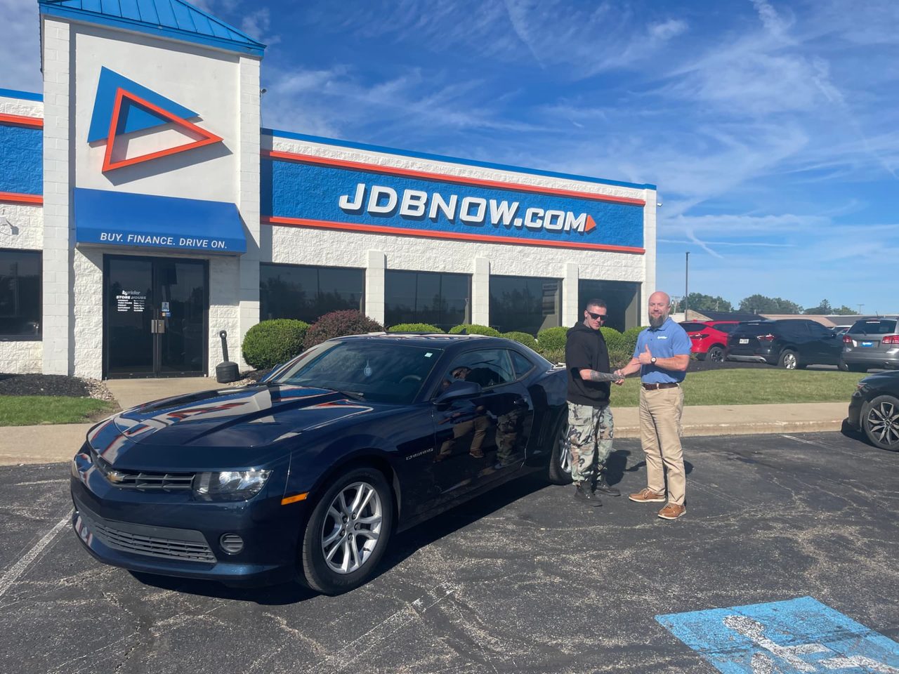 Byrider Mansfield customer and salesperson beside their used Chevrolet Camaro at the Mansfield, Ohio dealership