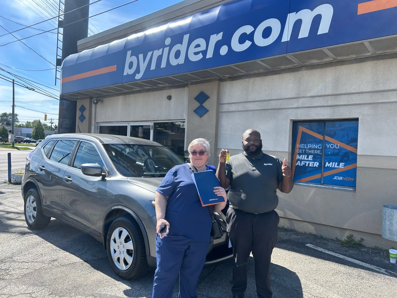 Byrider Cleveland customer and salesperson beside their used Nissan Rogue at the Cleveland, Ohio dealership