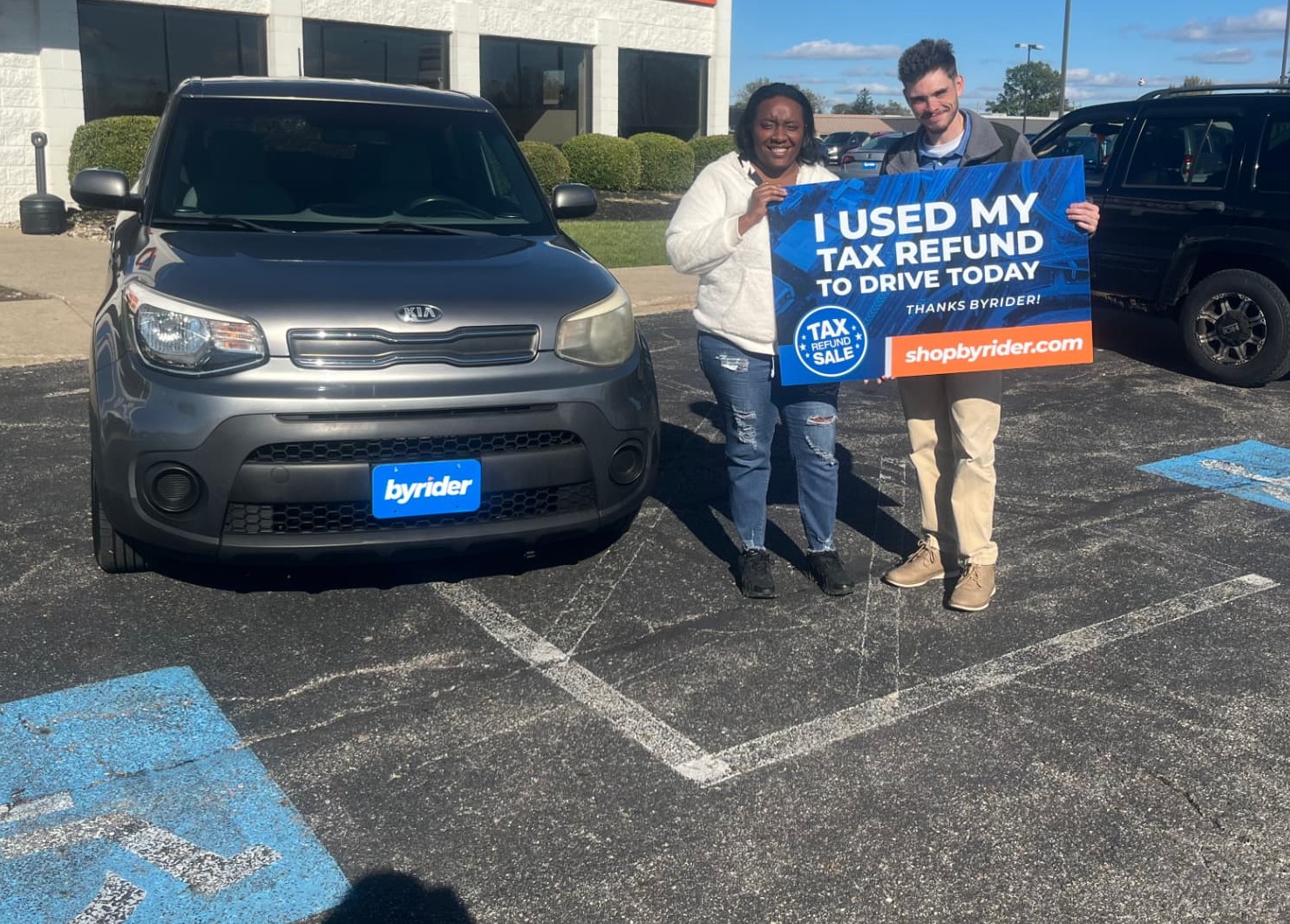 Byrider customers with their Kia Soul holding an I Used My Tax Refund to Drive Today sign during the Tax Refund Sale in Ohio