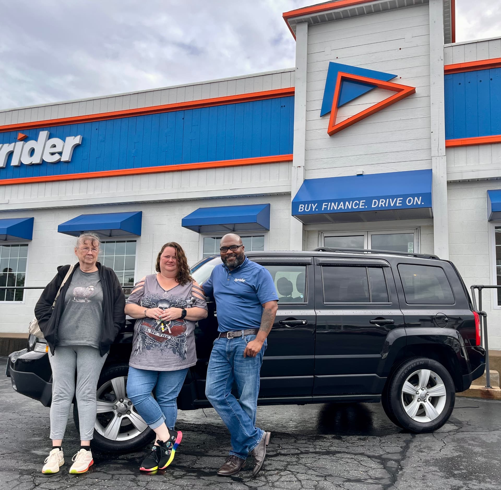 Byrider Canton customers and salesperson beside their used Jeep Patriot at the Canton, Ohio dealership