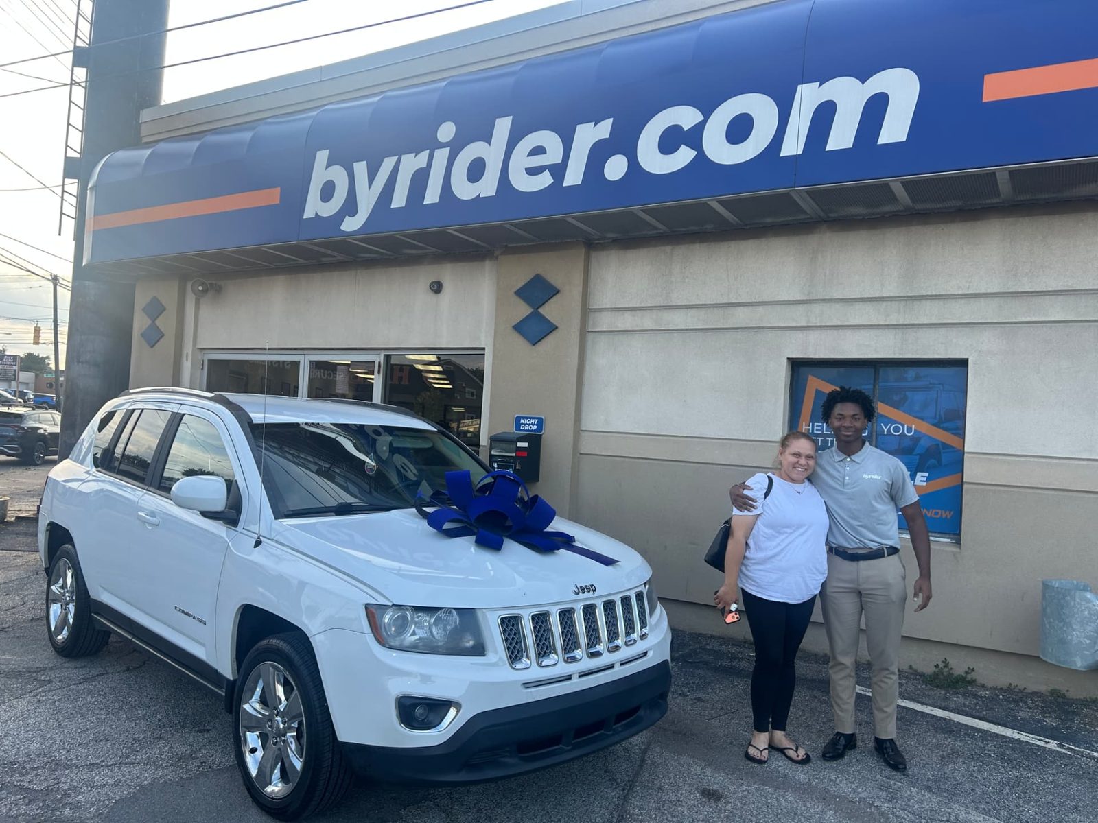 Byrider Cleveland customer and salesperson beside their used Jeep Compass at the Cleveland, Ohio dealership