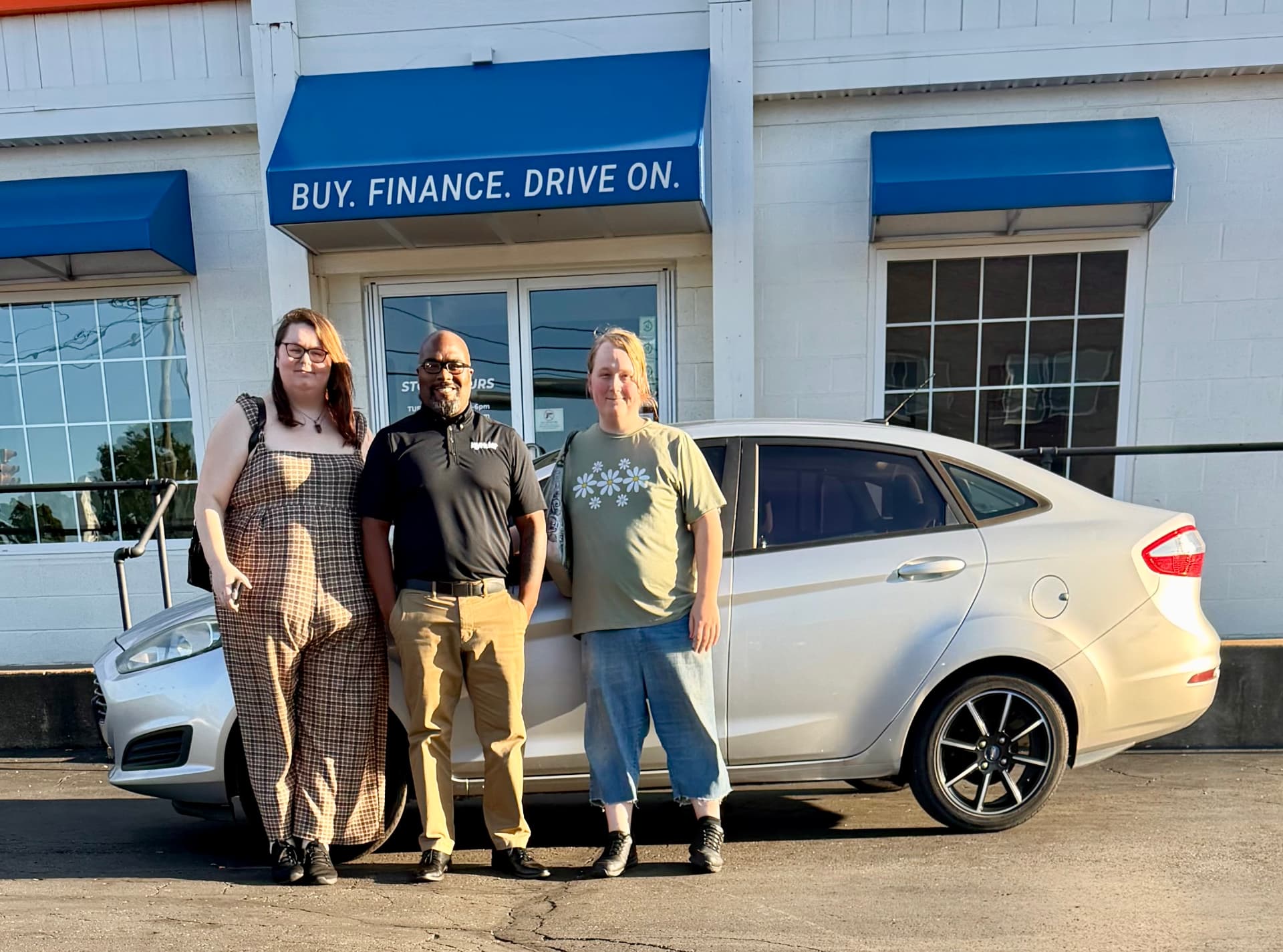 Byrider Canton customers and salesperson beside their used Ford Fiesta at the Canton, Ohio dealership