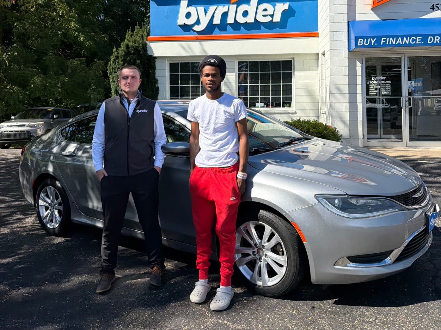 Byrider Wooster customer and salesperson beside their used Chrysler 200 at the Wooster, Ohio dealership